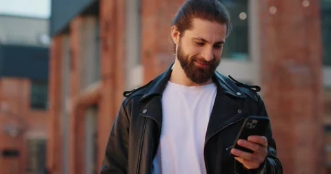 Man in leather jacket using social networks on his smartphone while standing. Stock Footage 246754101