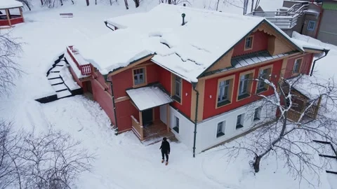 A man leaves the house in the yard in the winter. View from the drone winter Stock Footage 239464387