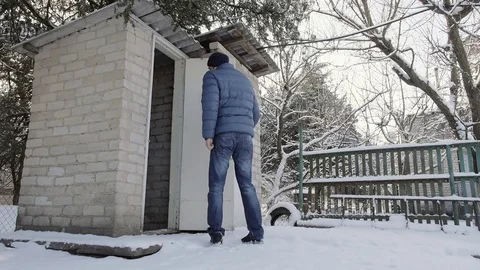 The man left and closed the door in the brick toilet in the village in winter Stock Footage 72414375