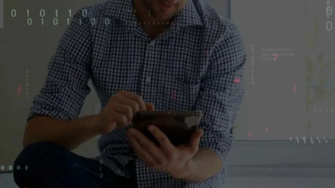 Man leg-crossed tapping tablet, bringing code overlays as camera lifting and Stock Footage 331227621