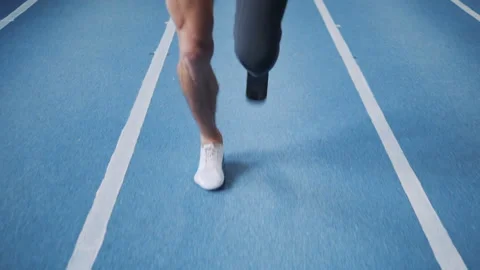 Man with leg prosthesis running on a training track, close up. Video stock 100832914