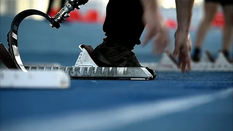 Man with leg prosthetics at the sprint start line in track and field competition 스톡 동영상 72900548