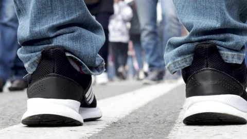 Man legs on double white line close up and lot of people walking Stockbeeldmateriaal 219958784