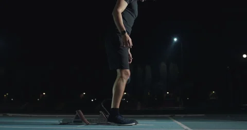 Man with legs prosthesis warms up before run with dedication at night. Stock Footage 154009309