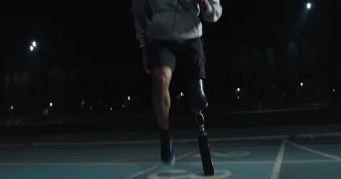 Man with legs prosthesis warms up before run with dedication at night. Stock Footage 154009330