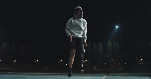 Man with legs prosthesis warms up before run with dedication at night. Stock Footage 154009367