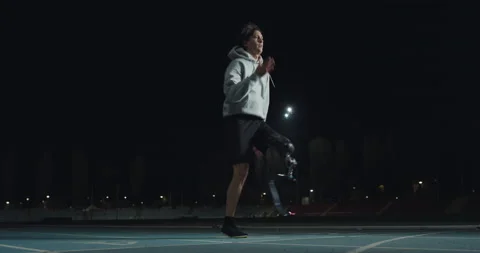 Man with legs prosthesis warms up before run with dedication at night. Stock Footage 154009424