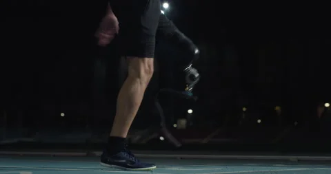 Man with legs prosthesis warms up before run with dedication at night. Stock Footage 154009438