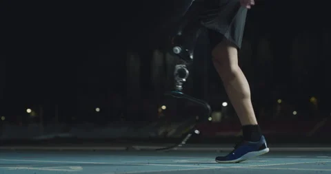 Man with legs prosthesis warms up before run with dedication at night. Stock Footage 154009447