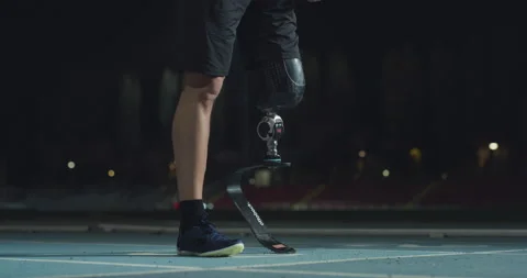 Man with legs prosthesis warms up before run with dedication at night. Stock Footage 154009451
