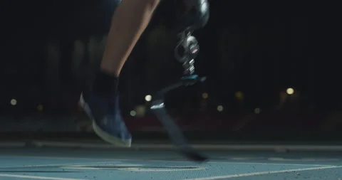 Man with legs prosthesis warms up before run with dedication at night. Stock Footage 154009463