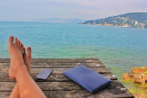 Man legs on the wooden table with mobile phone and laptop Stock Photos