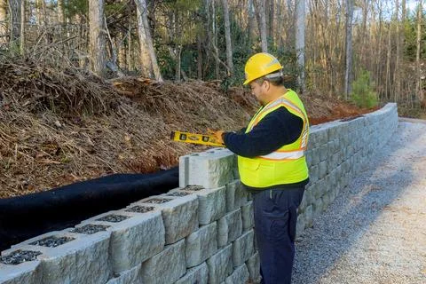 A man leveled a concrete block wall that was being built with the aid of his Foto stock