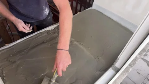 Man leveling concrete on wide interior windowsill Stock Footage 346709972