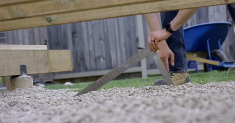 Man leveling gravel while building backyard deck - close up on hands Stock Footage 140483814