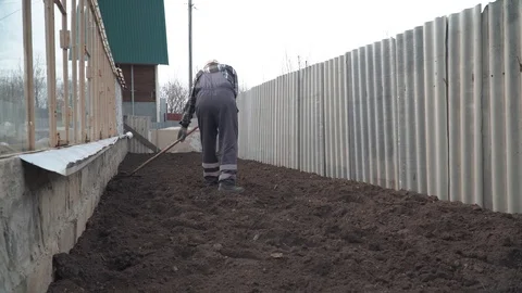 Man leveling the ground with a rake Stock Footage 96361602