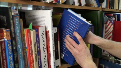 Man in the library chooses a book from the bookshelf Stock Footage 155962876