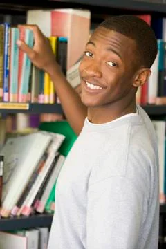 Man in library pulling book off shelf Stock Photos