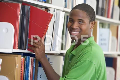 Man in library pulling book off a shelf (depth of field) Stock Photos