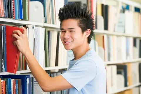 Man in library pulling book off a shelf (depth of field) Stock Photos