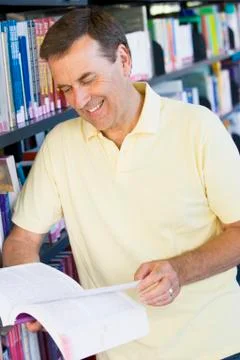 Man in library reading book (depth of field) Stock Photos