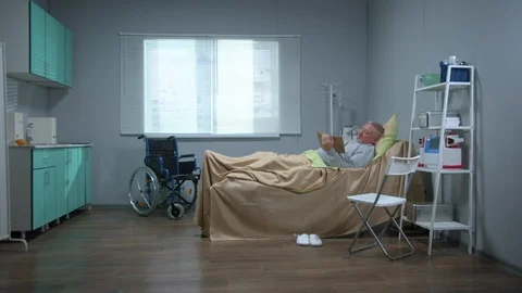 Man lie on the bed in the hospital and watch something on tablet Stock Footage 123681853