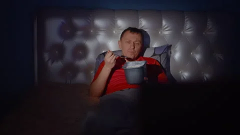 A man lies on the bed and eats ice cream, a boring bachelor evening Stock Footage 132301084