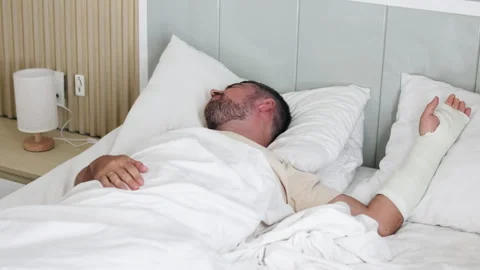 Man lies in bed with broken arm. Stock Footage 289542569