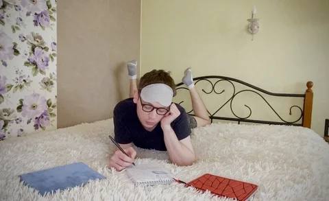 Man lies on bed studying work Stock Footage 129172044