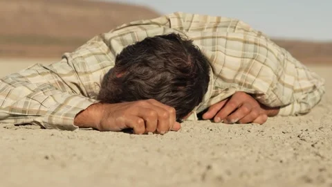 The man lies face down on the dry ground and tries to crawl forward Stock Footage 256078578