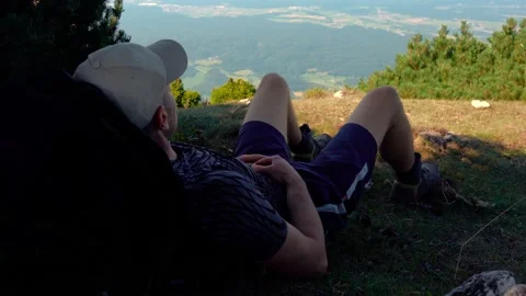 A man lies in the grass high in the mountains Stock Footage 202337765