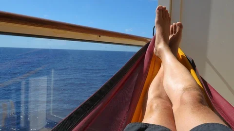 Man lies in hammock on the balcony of a cruise ship Stock Footage