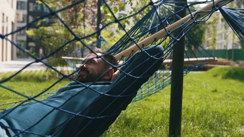 A man lies in a hammock in a public space Stock Footage 160939681