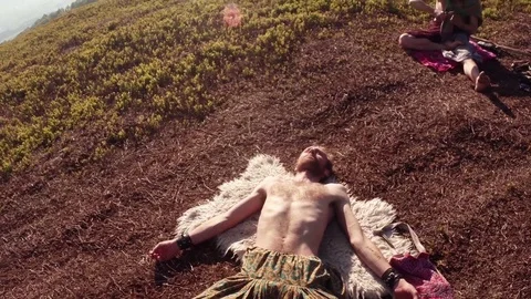 Man lies in a relaxed pose of a corpse on the skin of an animal next to another  Stock Footage 77784767