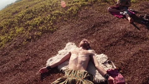 A man lies in a relaxed pose of a corpse on the skin of an animal next to anothe Stock Footage 77784806