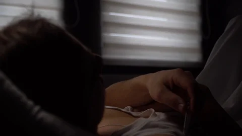 The man lies sick on the bed, checks the temperature, dramatic lighting Stock Footage 125809873