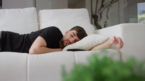Man lies on sofa feeling tired in living room at home Video stock 247206736