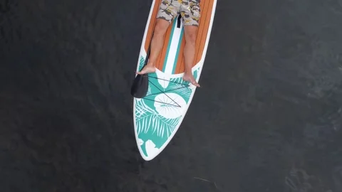 A man lies on a sup board on the surface of the lake. Cinematic top view. Stock-Footage 245262447