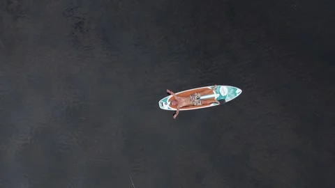 A man lies on a sup board on the surface of the lake. Cinematic top view. Stock-Footage 245262541