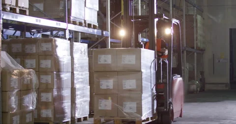Man Lifting Boxes With Forklift And Putting Them Onto Shelf Stock Footage 142892505