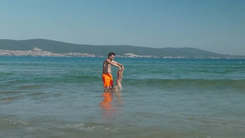 Man lifting child in surf playful summer Stock Footage 336202908