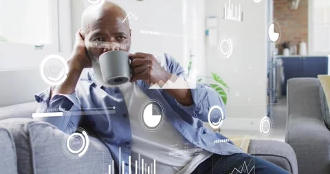 Man lifting coffee mug from sofa armrest and sipping while viewing animated tech Stock Footage 318936121