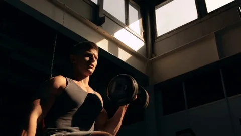 Man lifting dumbbell in sunlight 스톡 동영상 77877020
