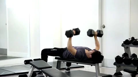Man lifting dumbbells lying on bench at the gym Video stock 50984059