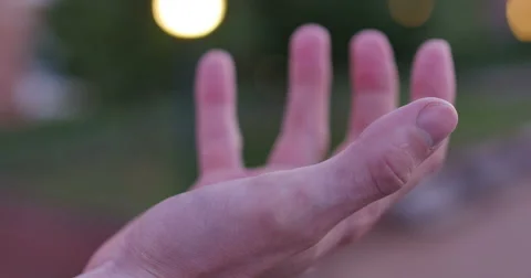 Man Lifting Hand and Makes Fist at Dusk with City Lights, 4K Stock Footage 65140508