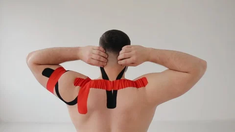 The man lifting his arms, back view. Athlete has kinesiotherapy after workout. Stock Footage 128990254