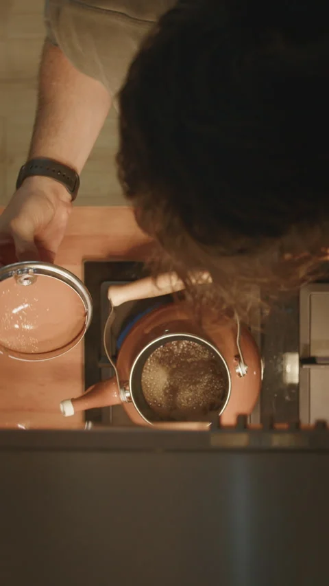 Man lifting lid off copper teapot to check tea brewing on stove, top down v.. Stock Footage 344487645