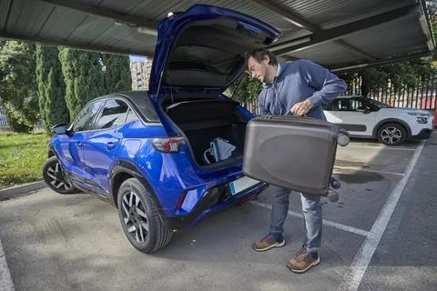 Man lifting suitcase to load into car trunk Stock Photos