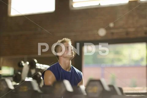 Man Lifting Weights In Health Club