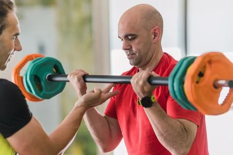 Man lifting weights with the help of a coach Stock Photos